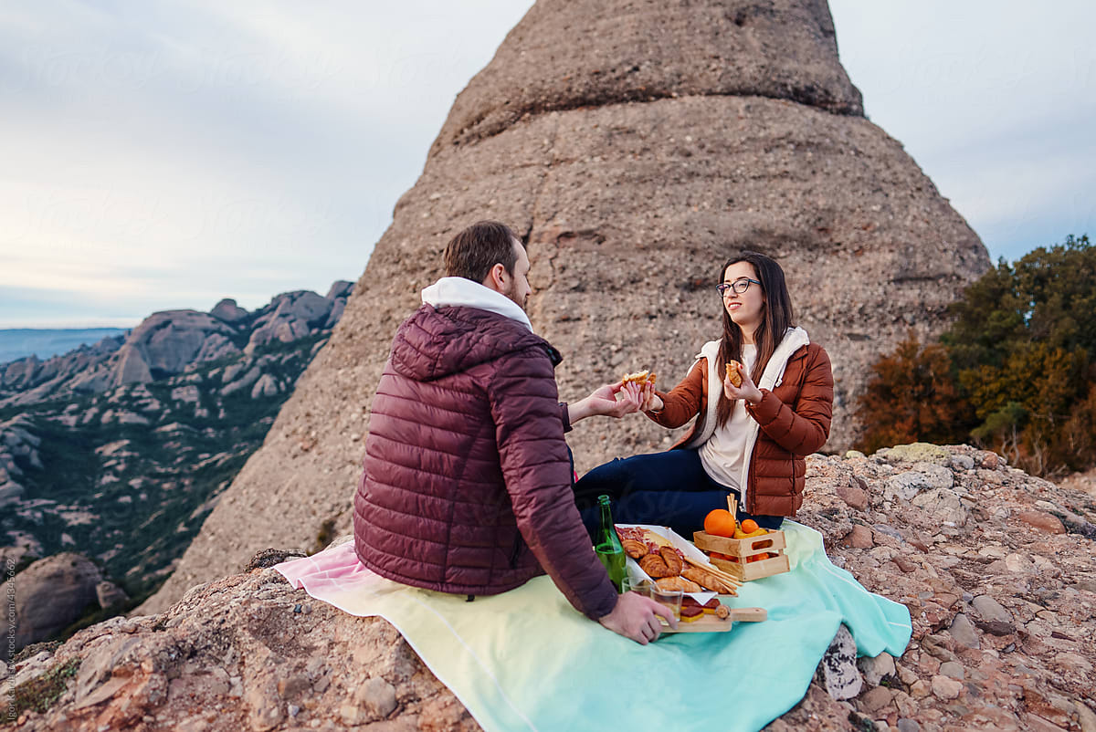 Couple eating picnic food on peak of rocky mountain