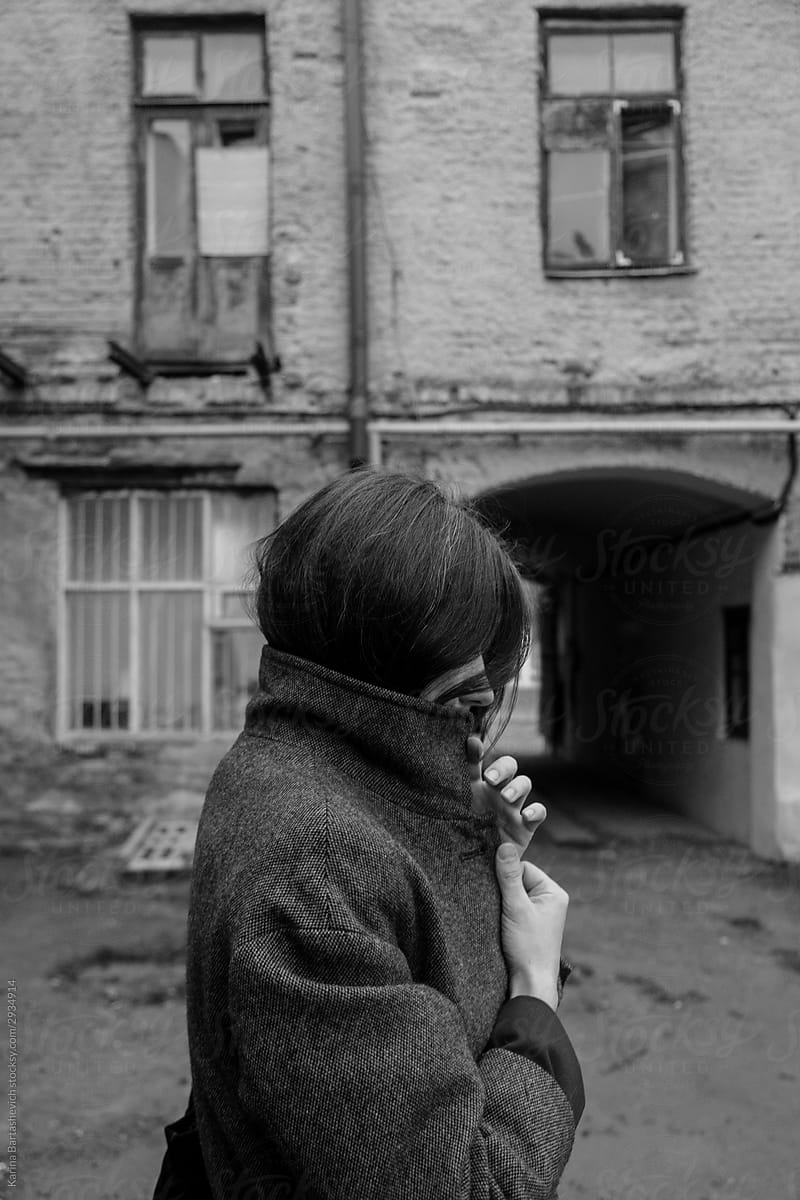 black and white photo of a girl in profile against the background of an old building while walking in the old city in autumn