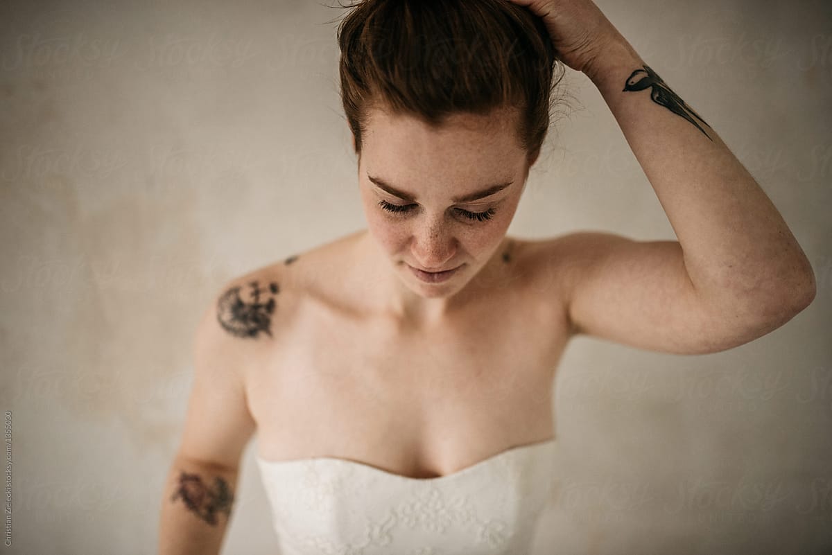 Tattooed bride adjusting hair for wedding celebration
