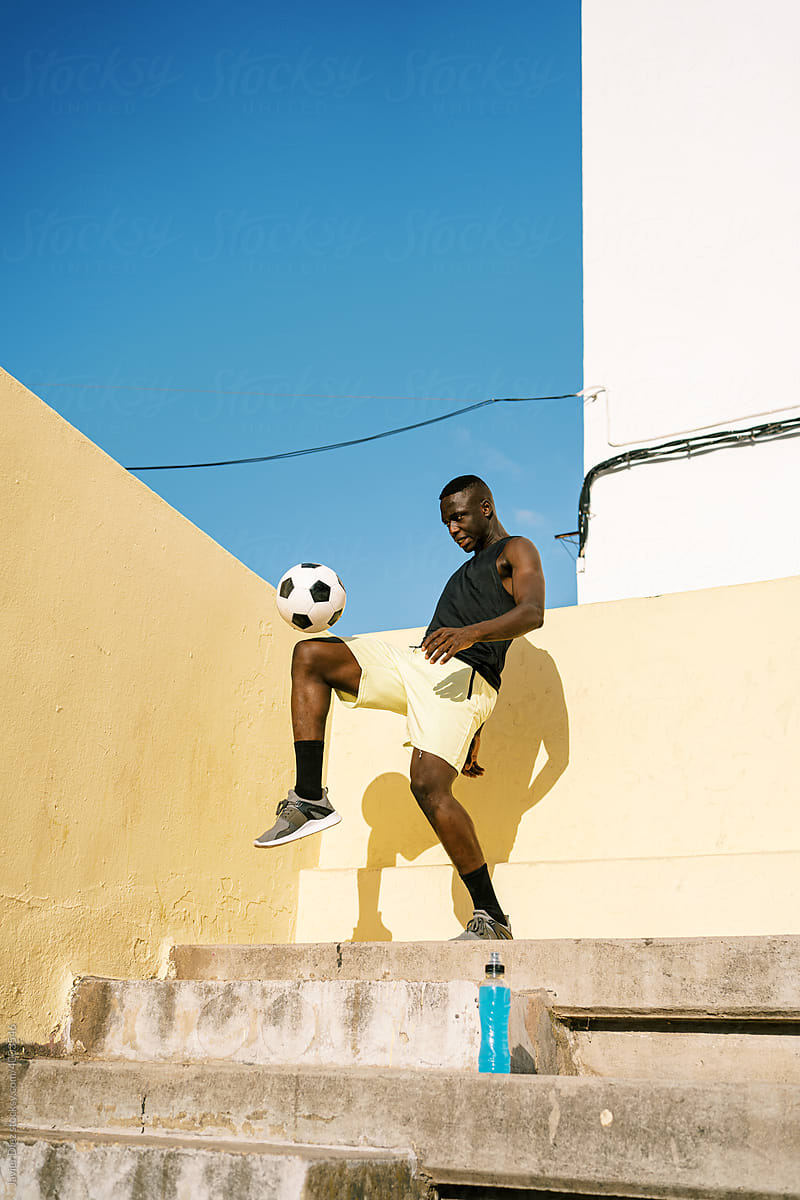 Black sportsman bouncing football ball