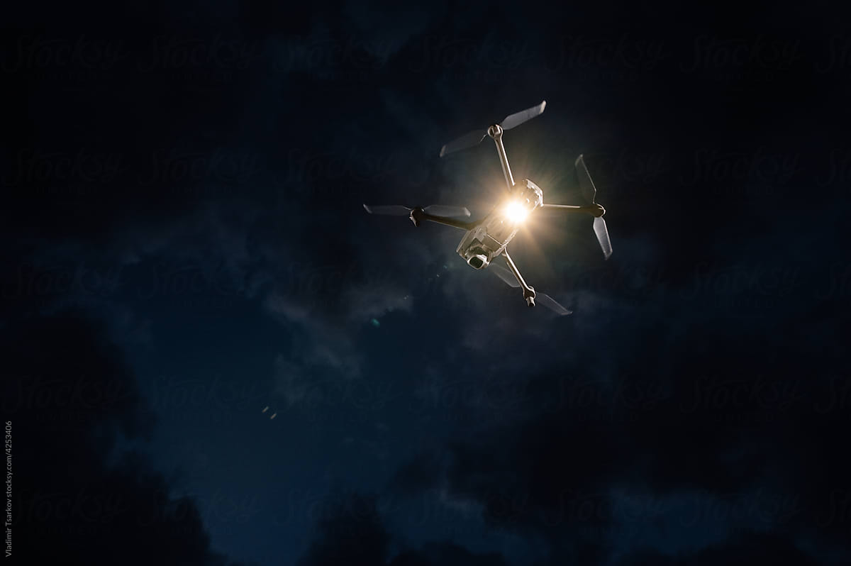Quadrocopter With flashlight Flies on night sky background