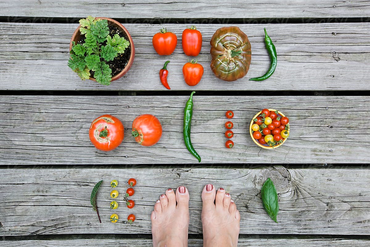 Woman's feet with garden harvest on wooden background