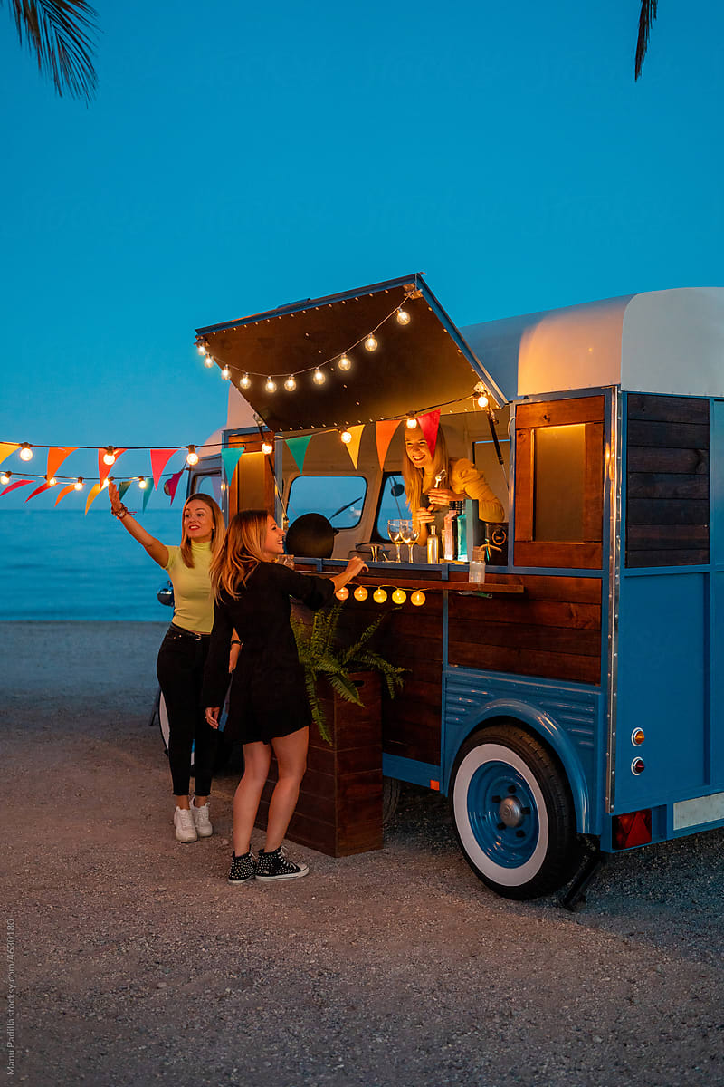 Girlfriends making order in food truck on beach