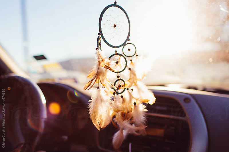 Dream catcher hanging from a car rear view mirror during a roadtrip by