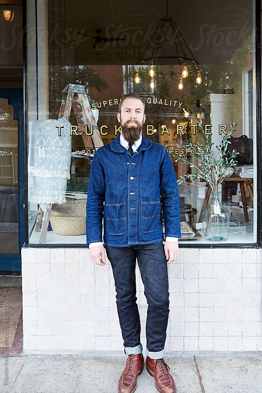 Portrait of hipster millennial small business owner standing in front of his artisan retail shop