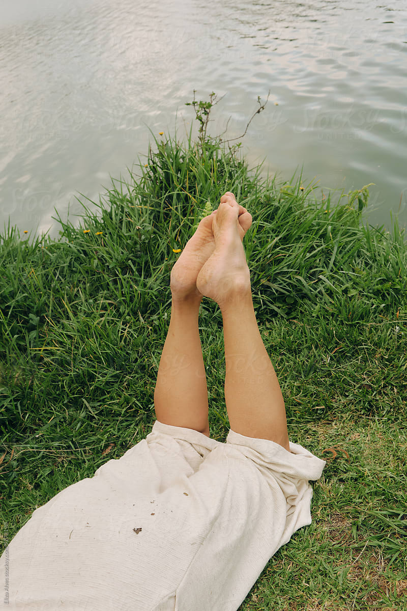 Legs resting in the grass next to a lake