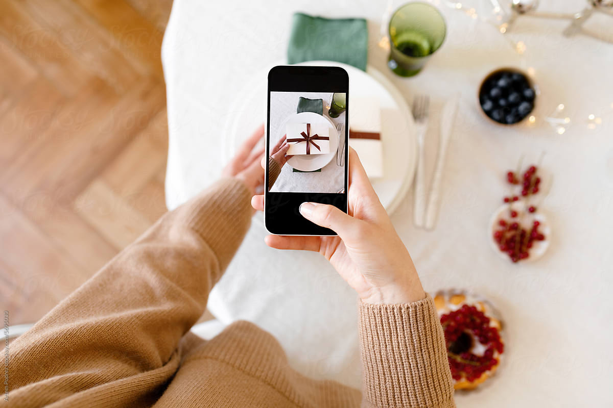A young woman takes photo of a Christmas gift on her phone