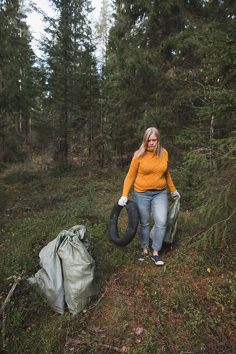 Woman collects plastic litter in the forest