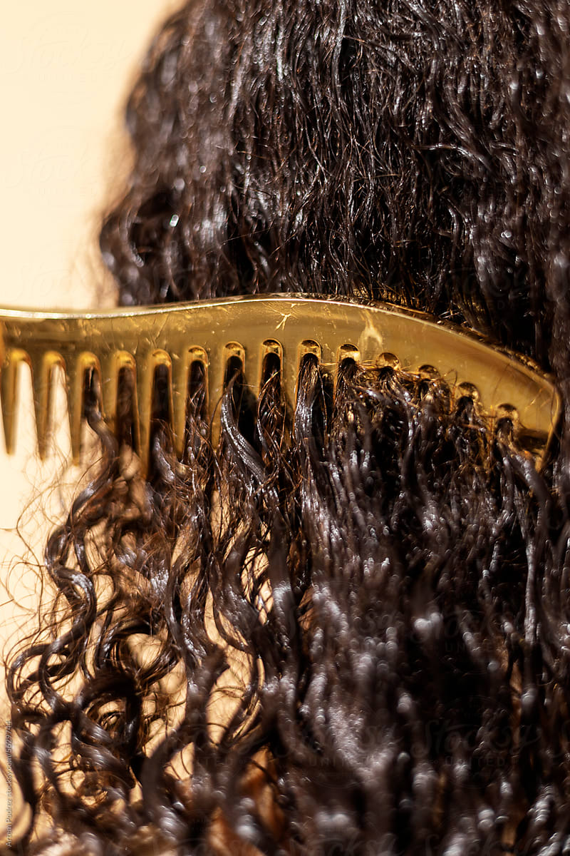 A woman combs her wet curly hair with a comb.