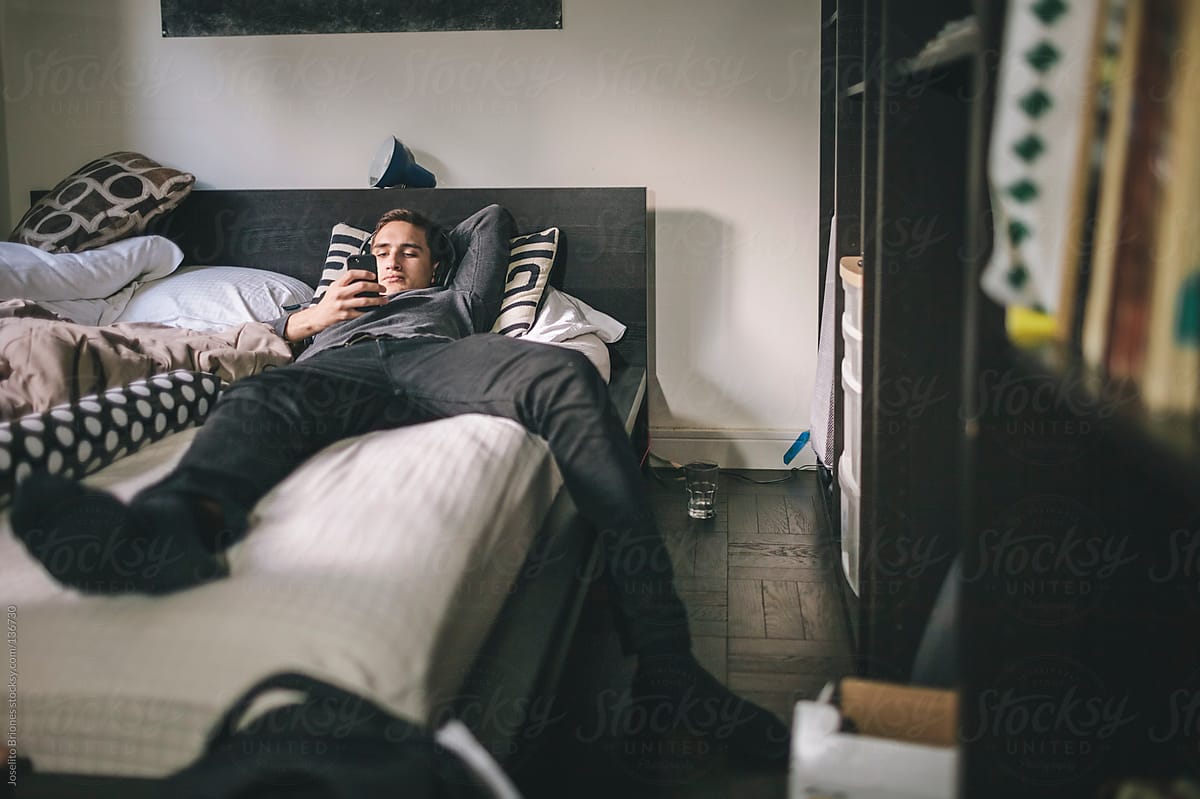 Young Mexican-American Man on Lazy Weekend Morning in Bed Using Smartphone