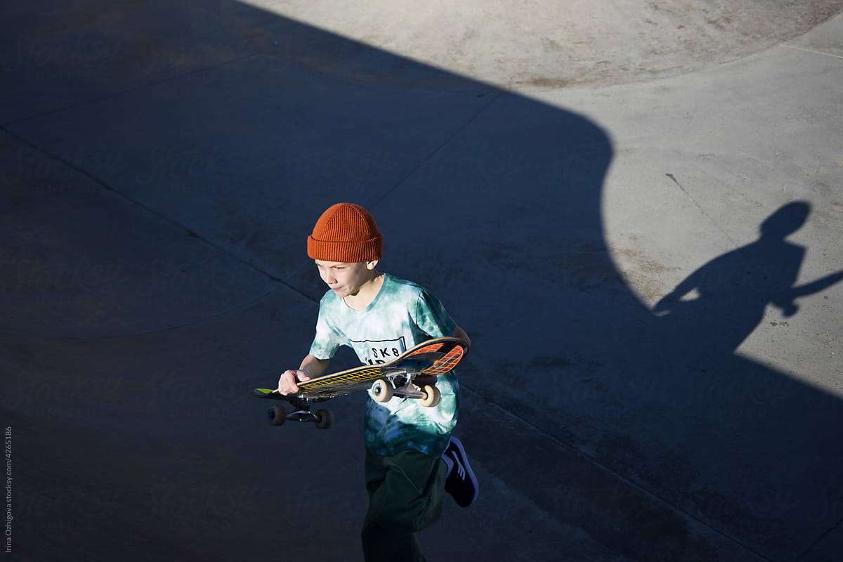 Teen skater with skateboard running in ramp