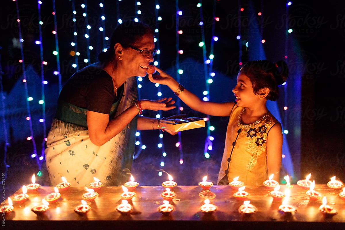 Little girl and her grandmother celebrating diwali with sweets