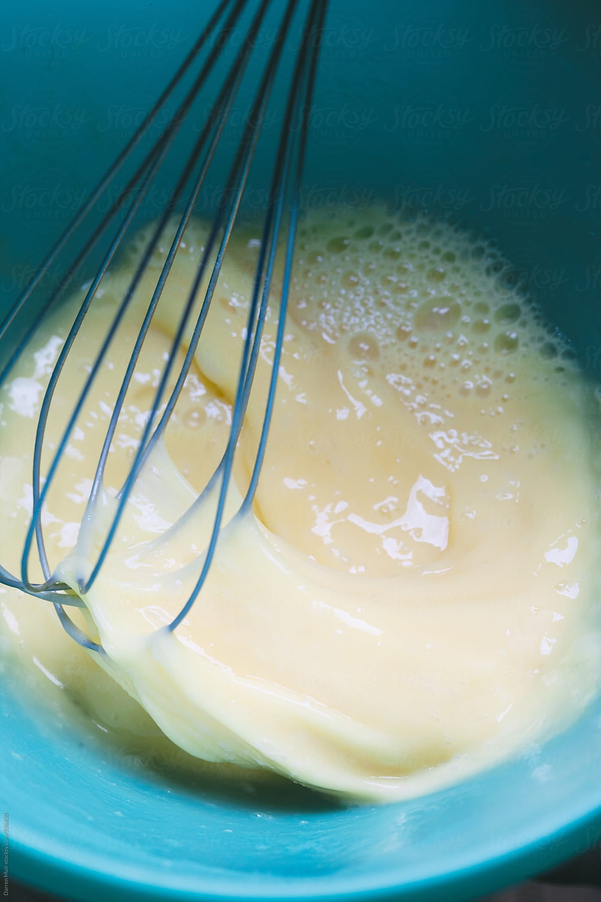 Beating eggs in a bowl with a hand whisk.