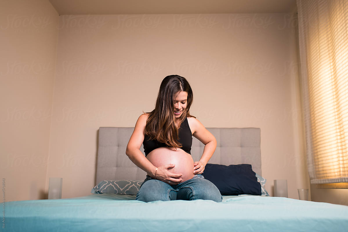 Smiling pregnant woman feeling baby kicks