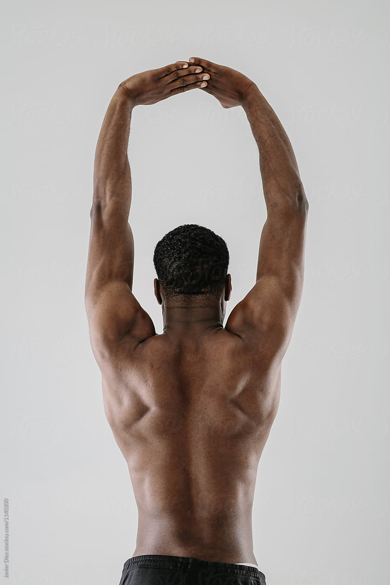 Rear view of topless sportsman with arms raised above head