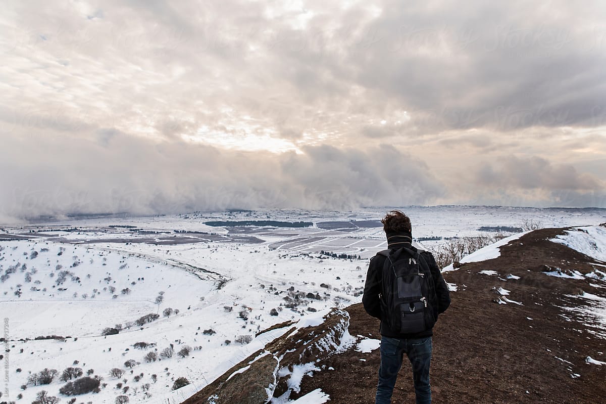 Man standing on a mountain looking at snow storm