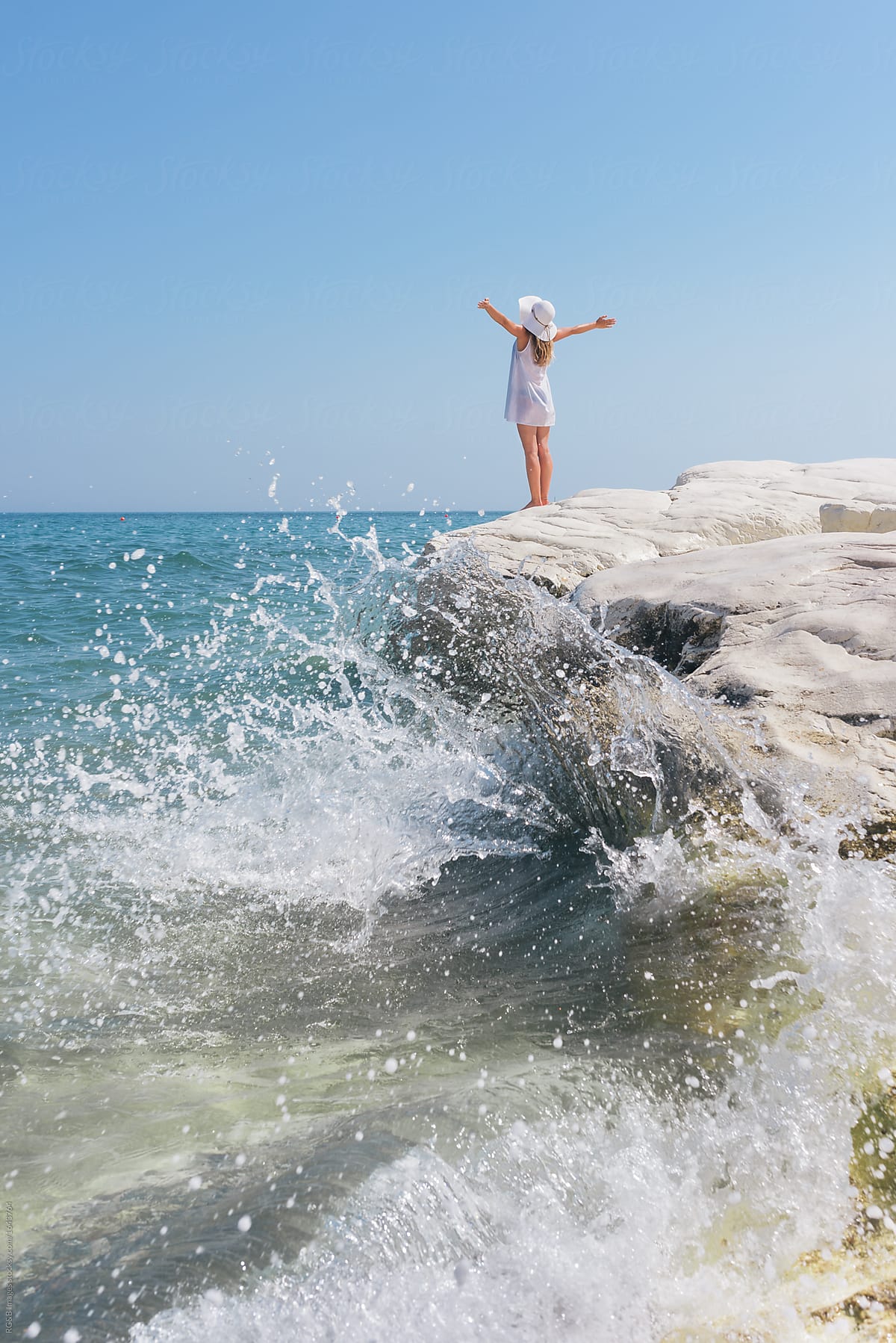 Woman with outstretched arms enjoying the seascape standing on a cliff