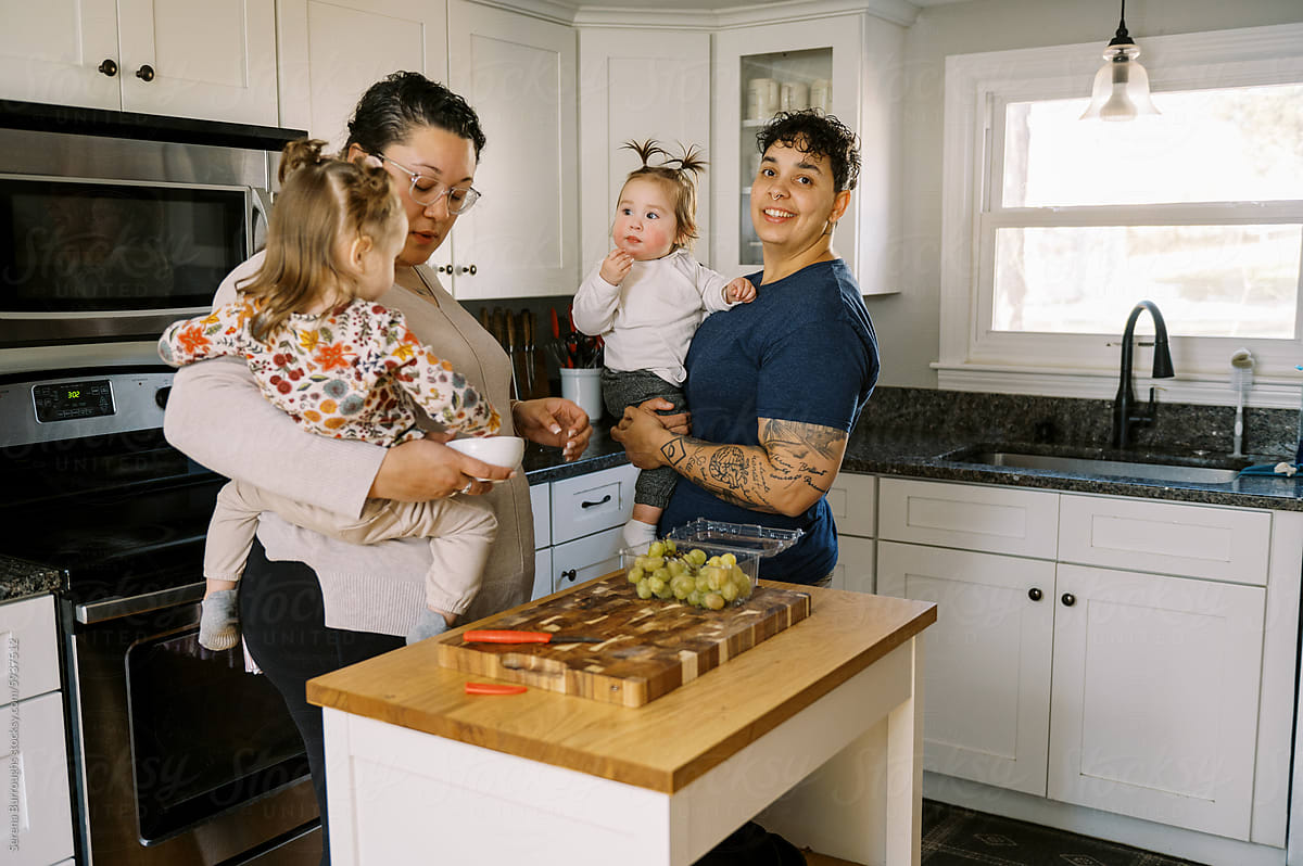LGBTQ Family with children standing in kitchen and having a snack