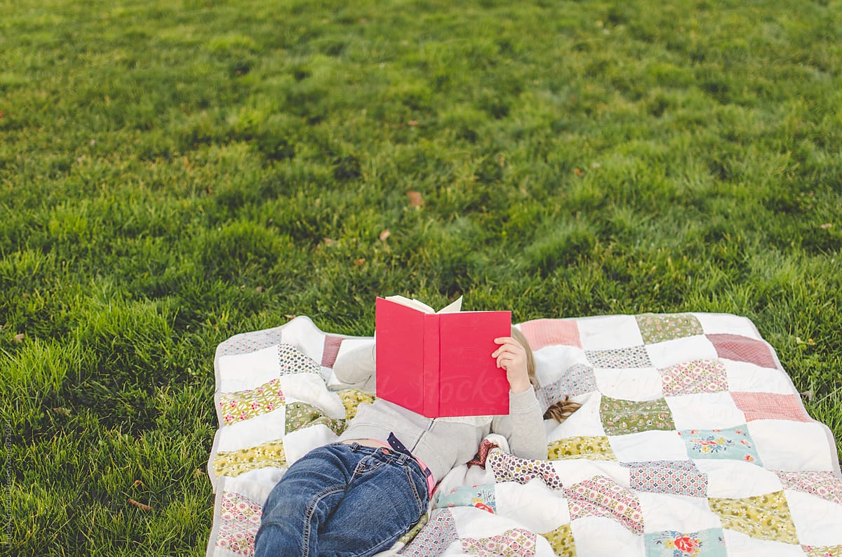 Child reading on a picnic blanket