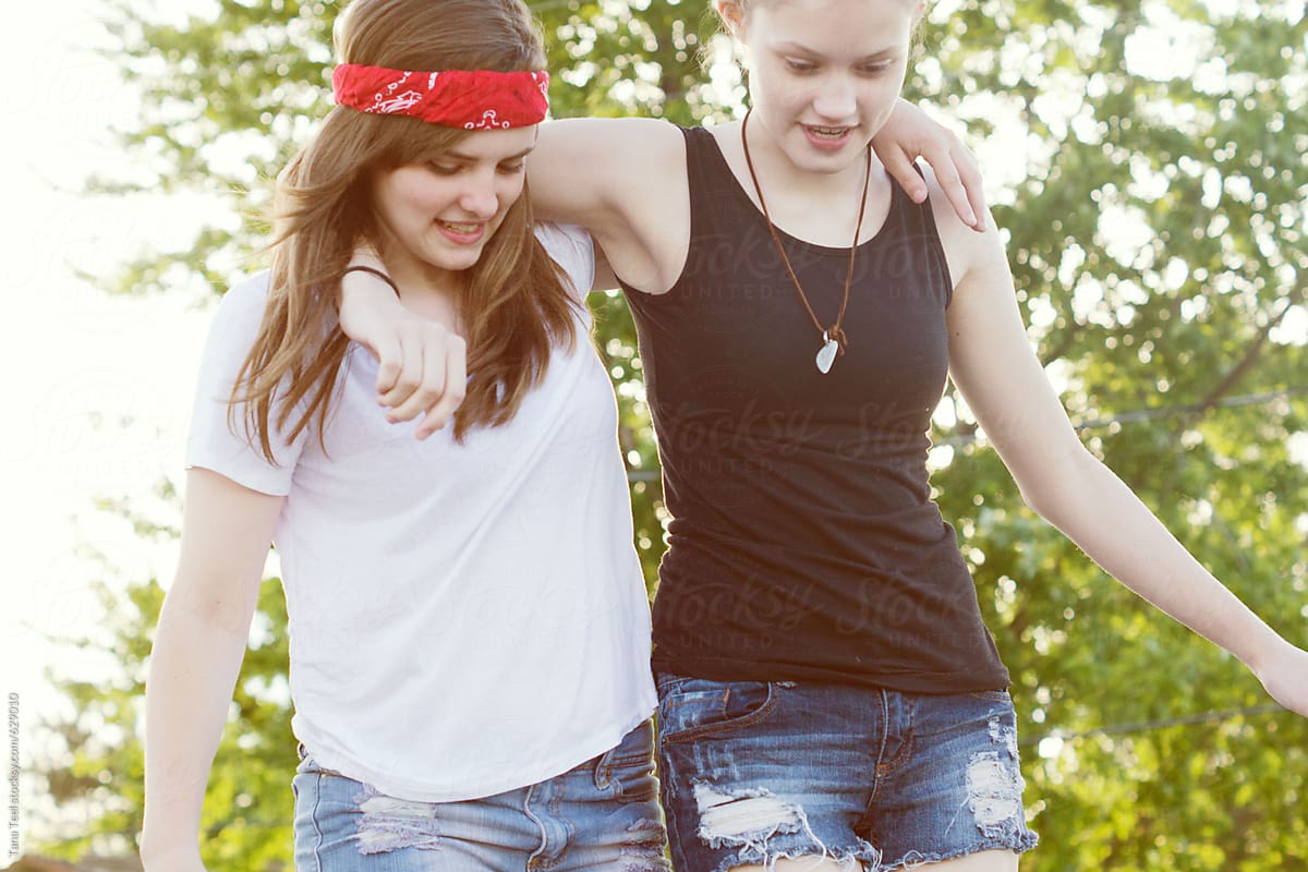 Teenage friends arm in arm on a roof top