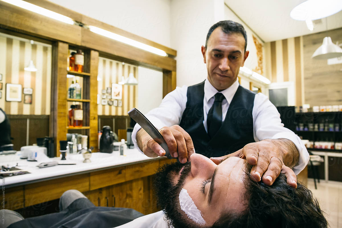 Man shaving client in salon