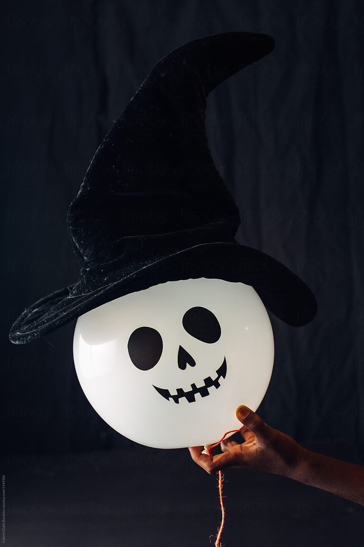 Spooky Halloween balloon with wich hat in child\'s hand