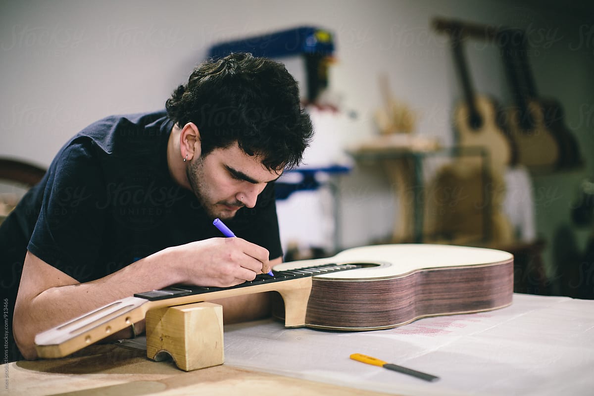 Young luthier building spanish guitars in his workshop