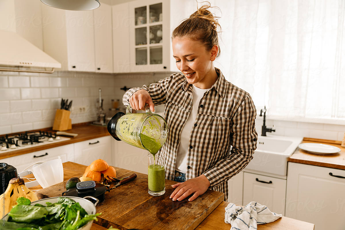 Girl pouring smoothie for breakfast in the kitchen