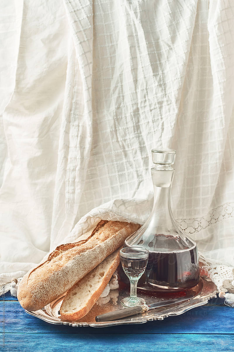 Cut baguette, decanter with red house wine and a glass on a meta