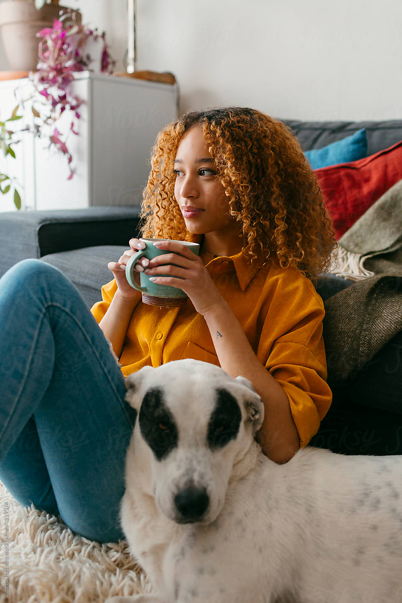 Teenager at home drinking tea with dog