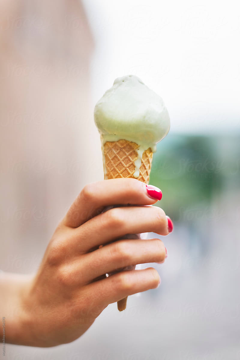 Hand Holding a Melt Ice Cream Cone .Close up