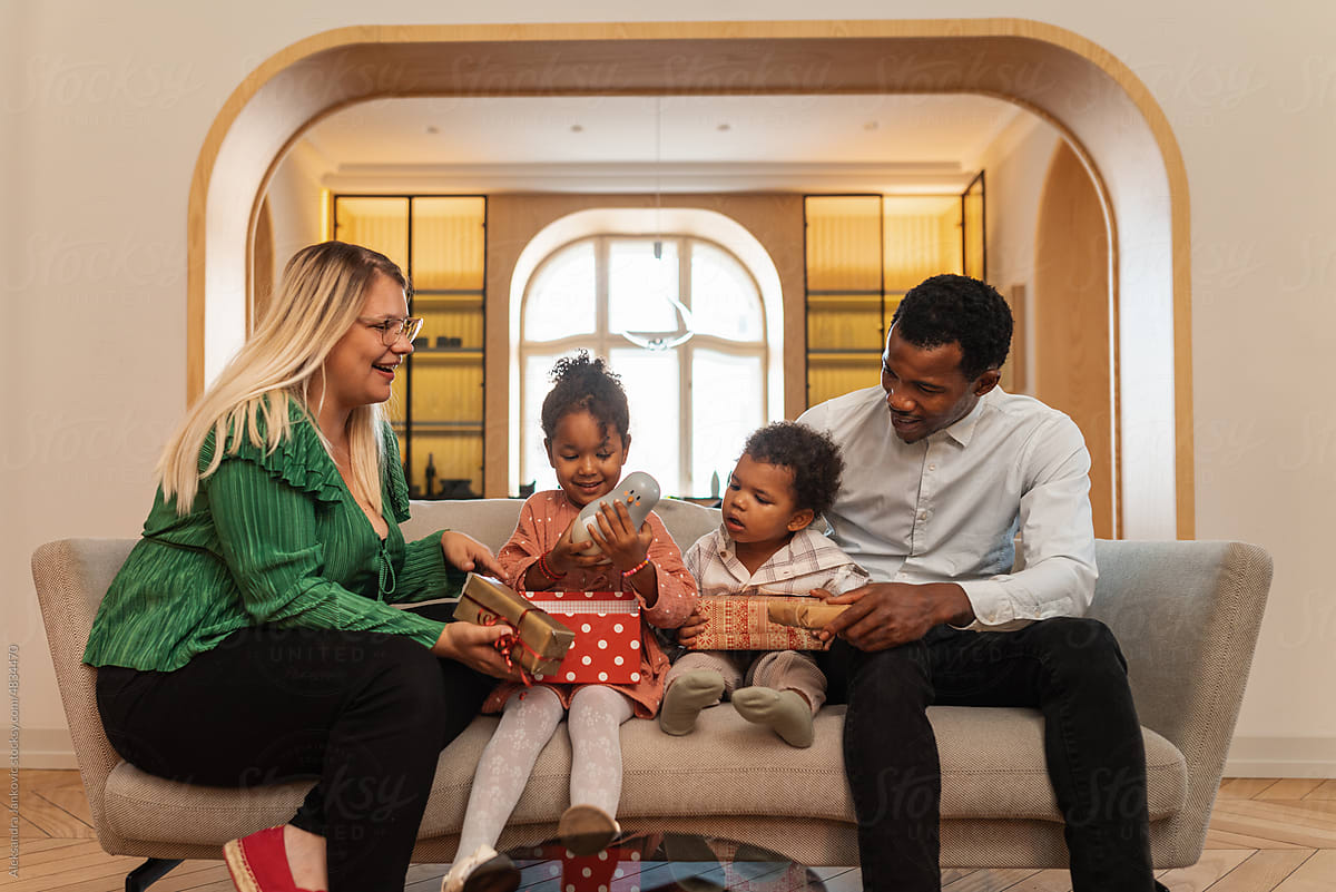 Diverse Family Opening Christmas Presents In The Living Room