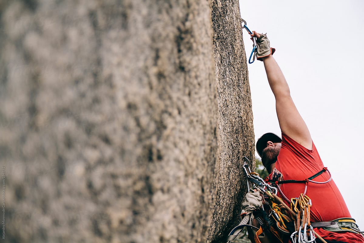 Aid climbing - Man reaching bolt while climbing a route