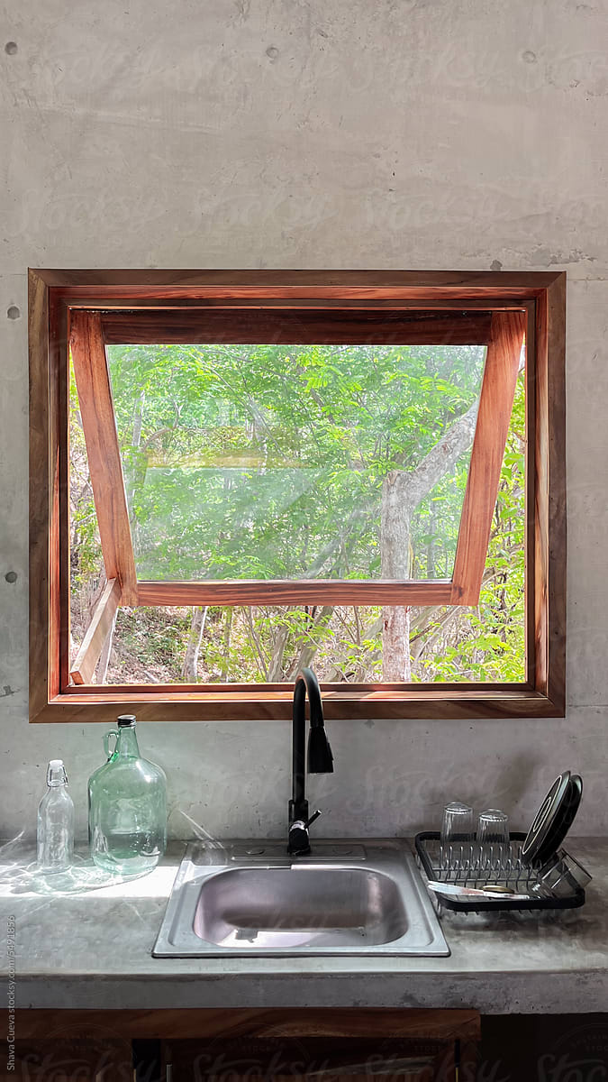 a sink in a kitchen with a wood-framed window