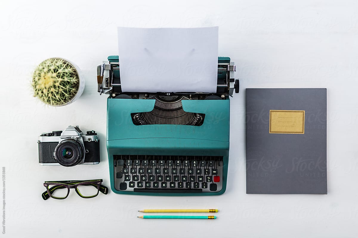 Vintage typewriter, notes and camera on a white wooden table