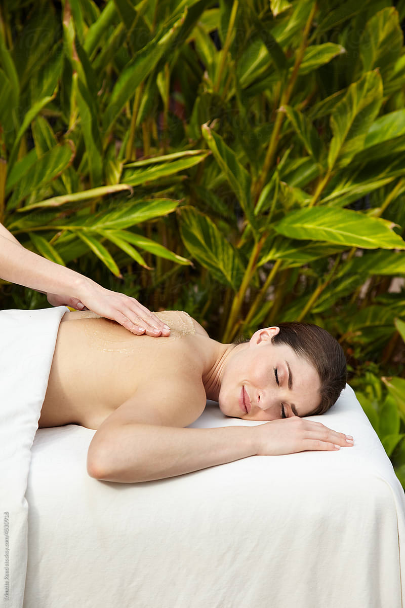 Woman receiving an exfoliating salt scrub massage spa treatment