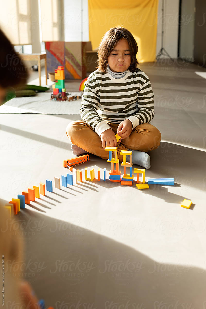 Boy playing with dominoes sitting on the floor