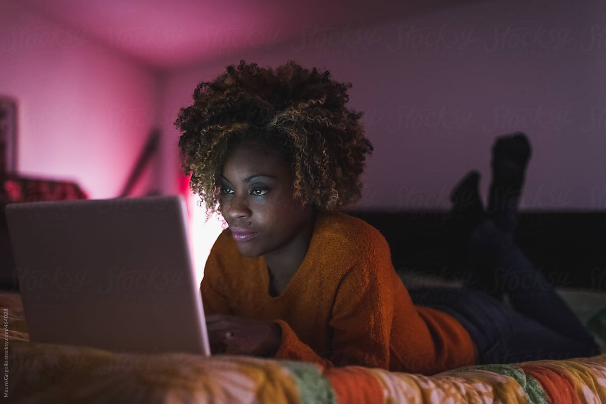 Black woman using laptop in the bedroom