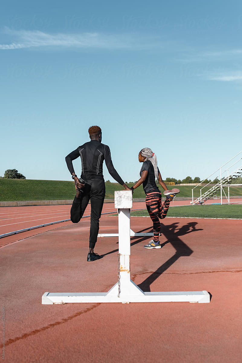 African American athletes standing near barrier and stretching legs