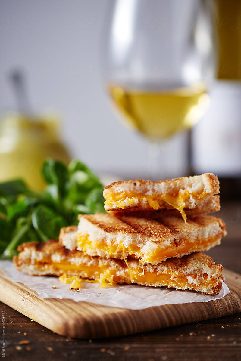 Grilled cheese sandwich on cutting board, white wine