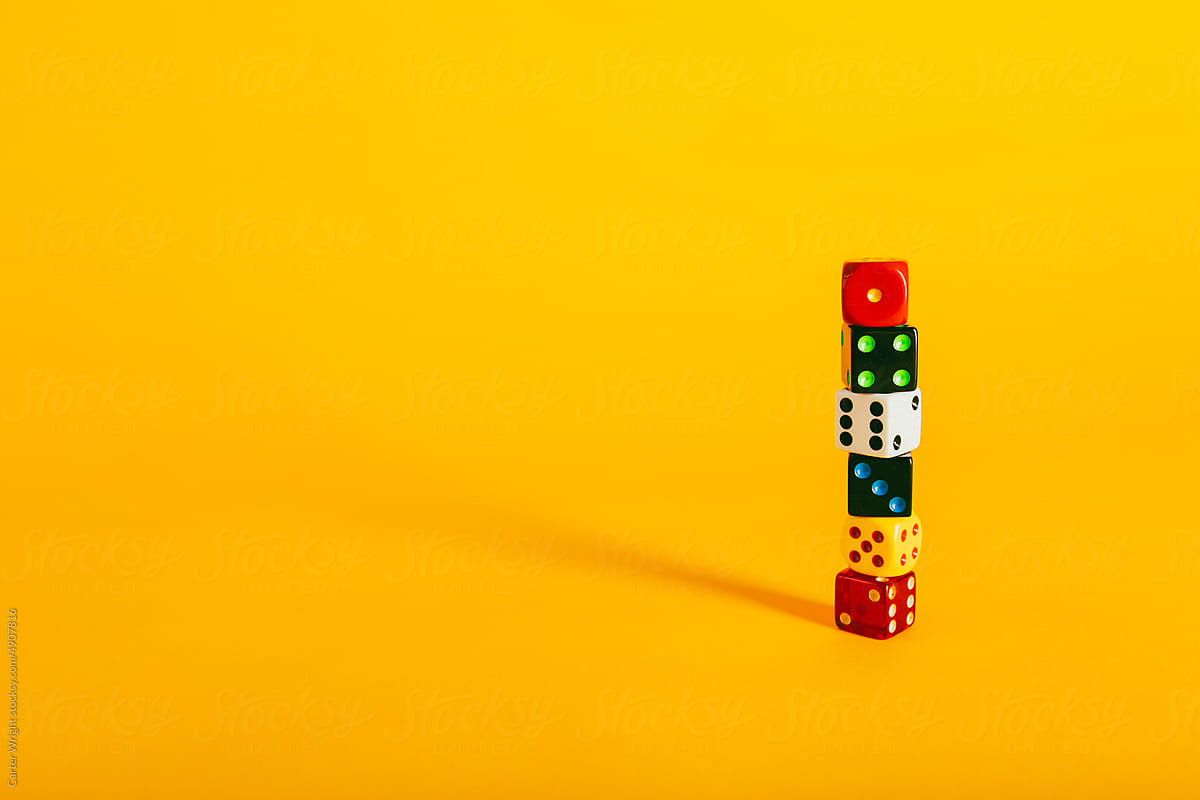 Colorful dice pieces and dice stacked on a vibrant yellow background