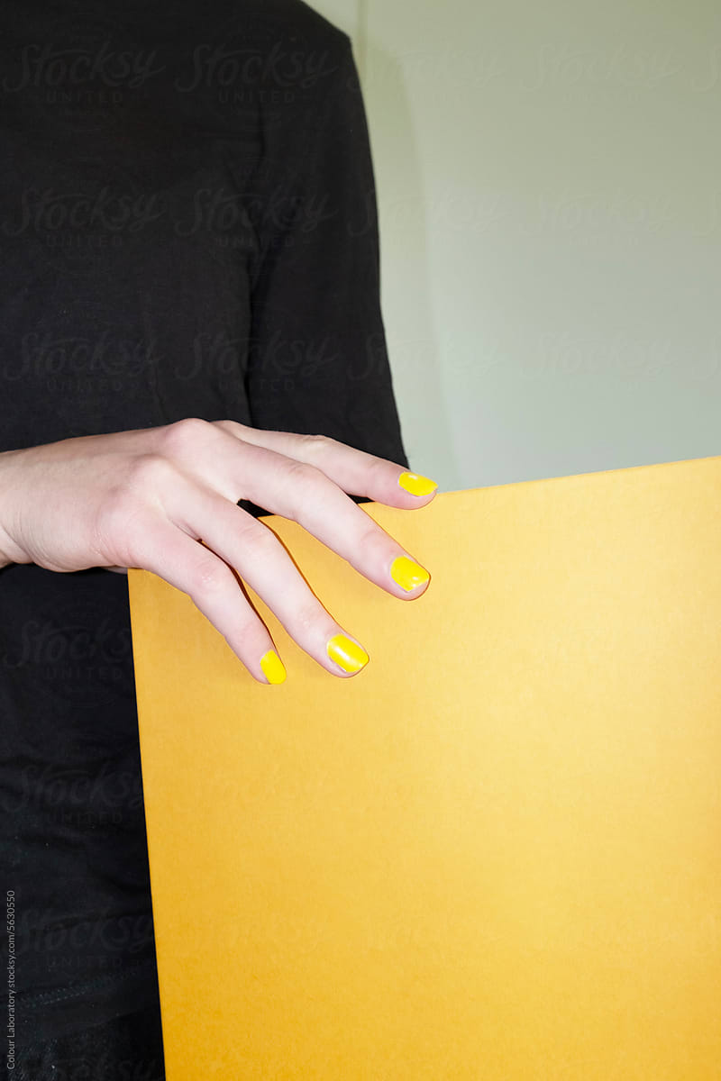 Person with yellow nails holding  yellow book with direct hard flash