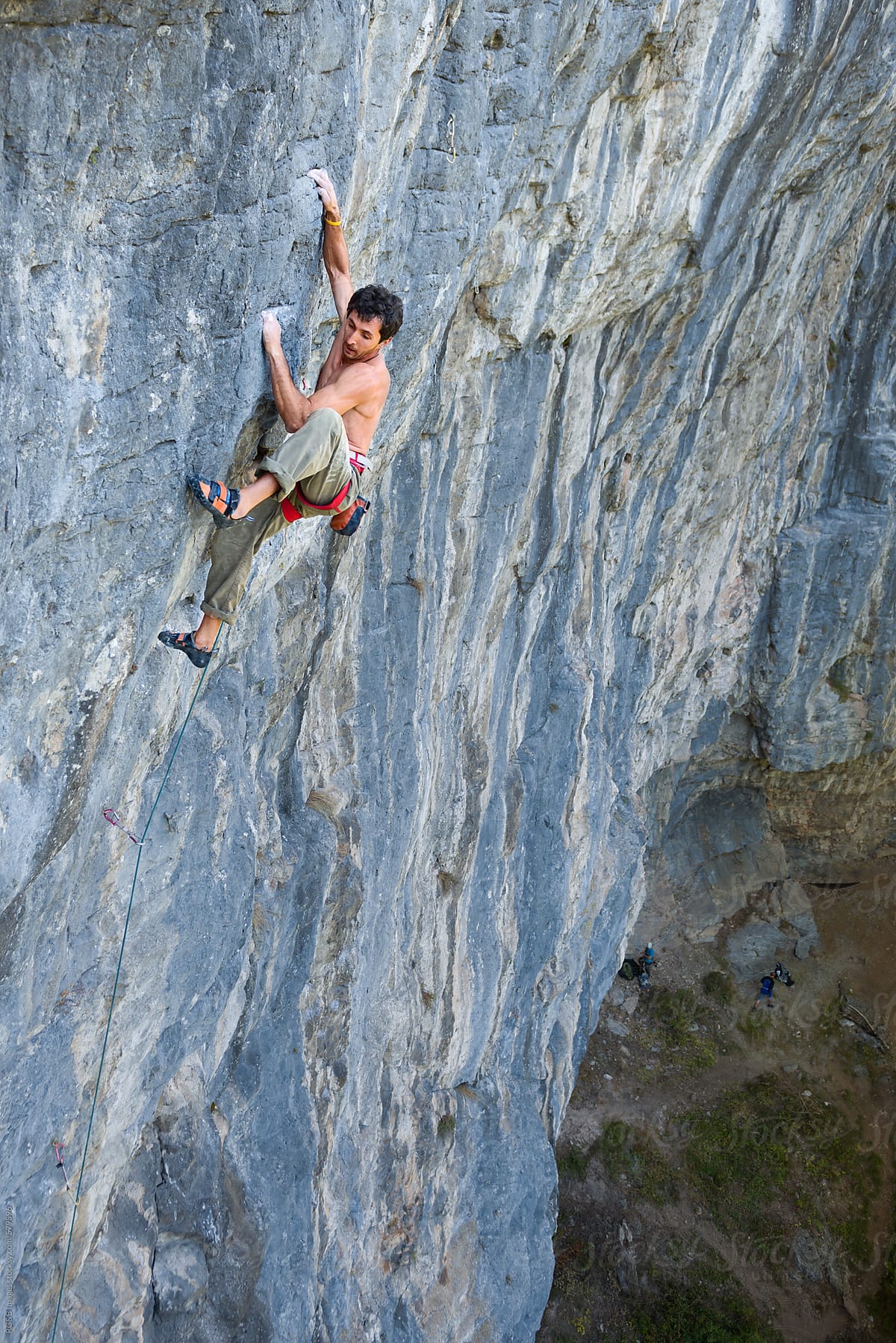 Male rock climber high above on the rock face