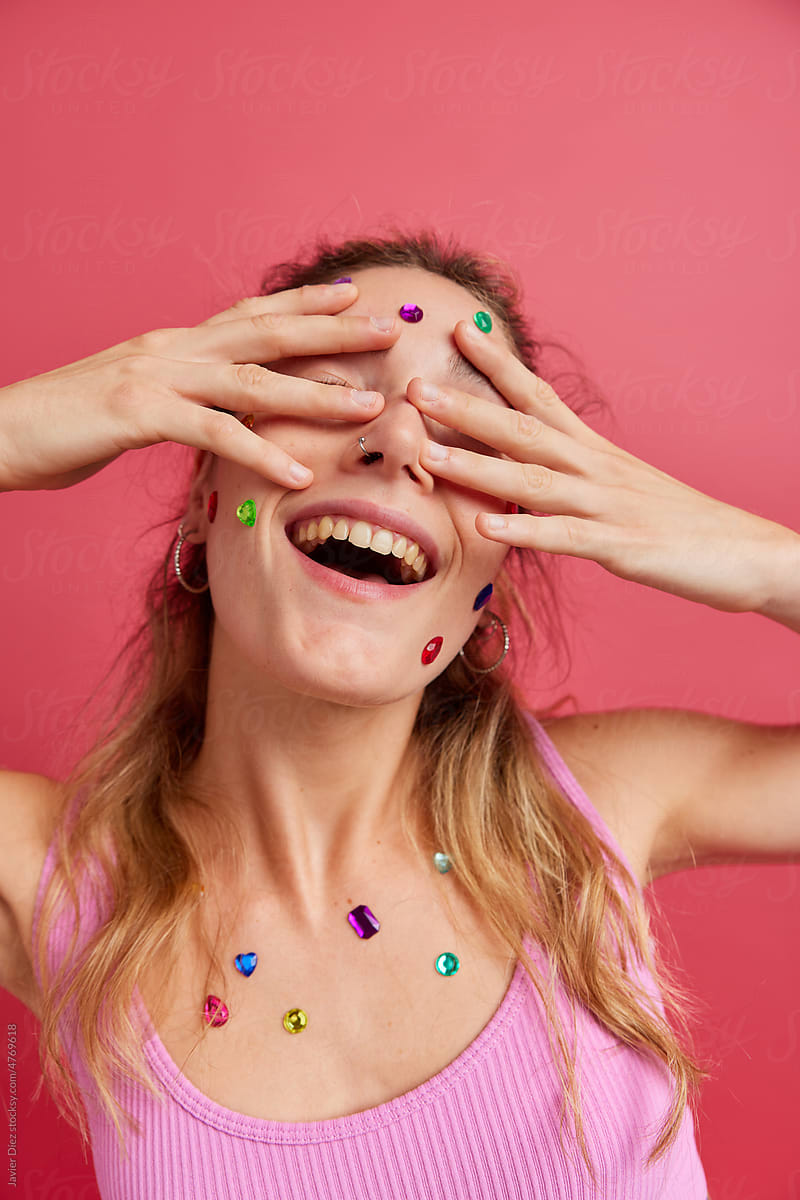 Happy lady with colorful gems on body smiling in studio