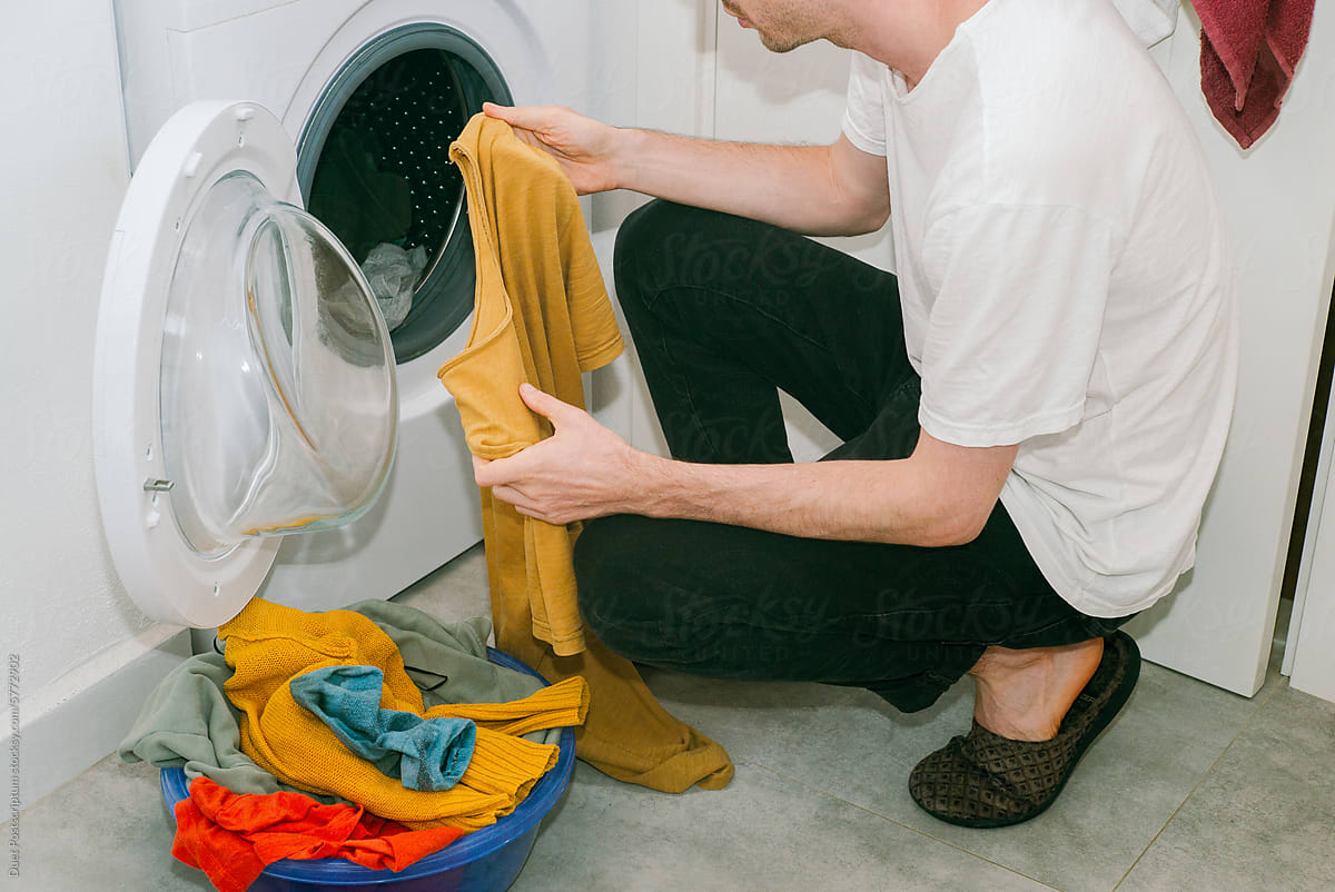 A young man sorting clothes before washing them