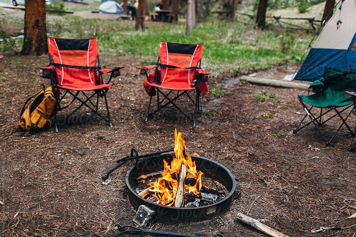 Folding camp chairs by an open pit fire in the forest