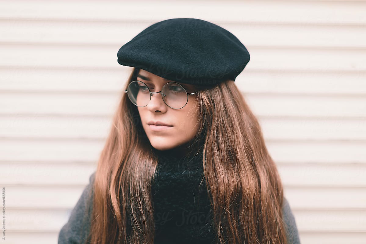 closeup of young woman with black hat and round glasses