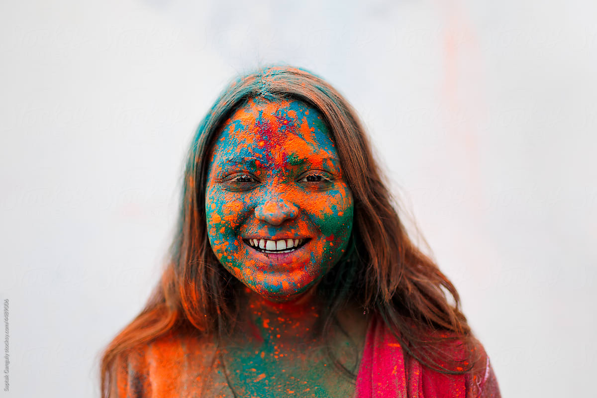 Smiling portrait of young woman smeared with color powders
