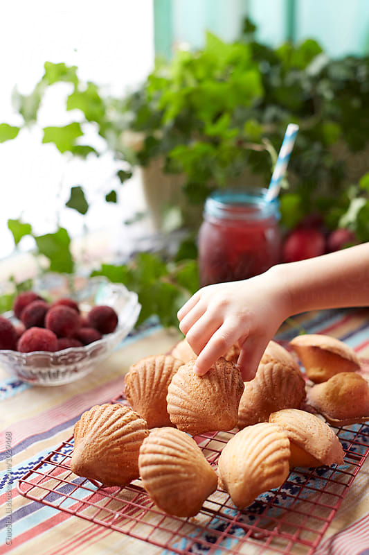 Fresh Madeleine on the table, a hand reaching for cake