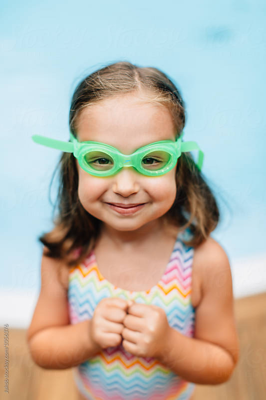 Close up portrait of a cute young girl with swim goggles by a pool